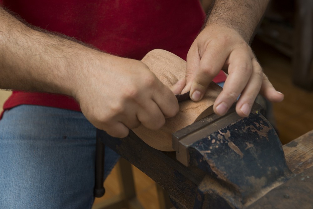 Hombre tallando madera en taller de talla en Escuela Luján Pérez